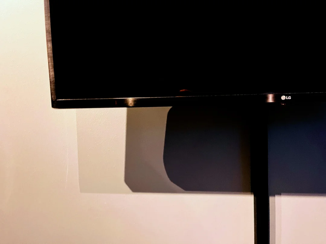 Televízor LG na stene so zrkadlením svetla, moderný dizajn interiéru.