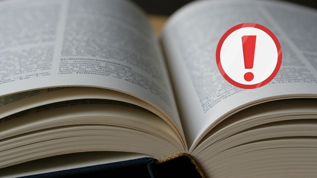 Otváranie knihy s upozornením na chyby v texte: symbol výkričníka na zvýraznenie nepresností.