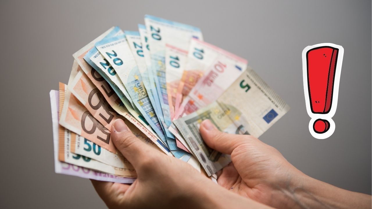 Osoba drží vejárovito rozložené euro bankovky, vedľa červený výkričník.