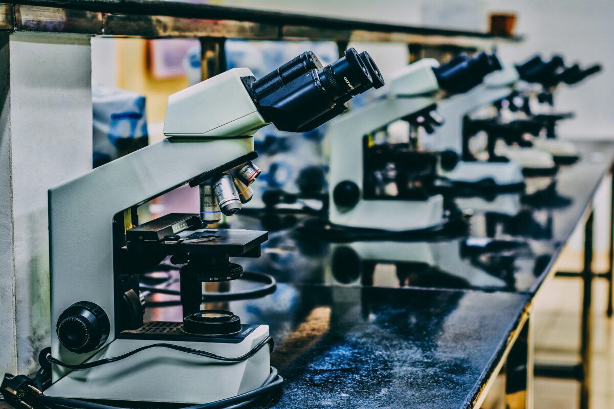 Riad mikroskopov na laboratórnom stole, pripravených na vedecké skúmanie.