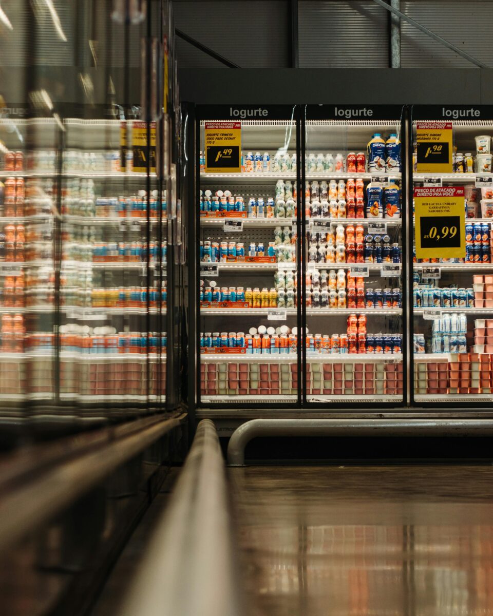 Chladiaci box v supermarkete plný rôznych druhov jogurtov a nápojov, ceny zvýraznené žltými ceduľkami.