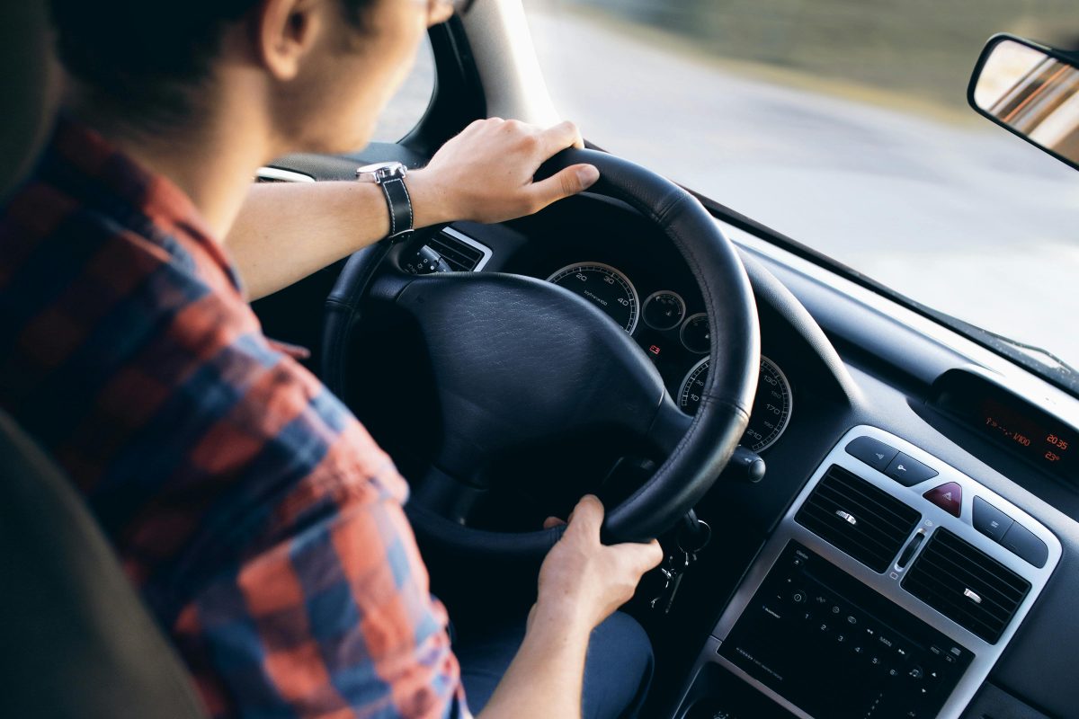 Osoba vodiaca auto, s pohľadom na cestu, vnútri vozidla s moderným interiérom.