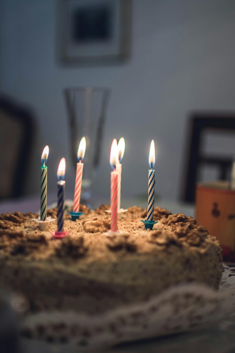 Narodeninová torta s orechami a sviečkami rôznych farieb, pripravená na oslavu.