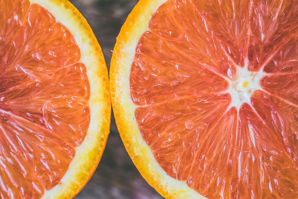 Dva rozpolené grapefruitové plátky, detailný záber s jasnými farbami a textúrou, vhodné do článku o zdravej výžive.