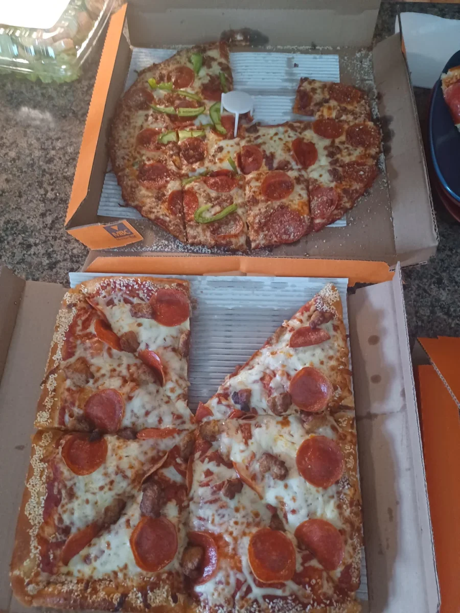 Dve pizze v krabiciach, jedna okrúhla s paprikou a salámou, druhá štvorcová s rôznymi druhmi mäsa.