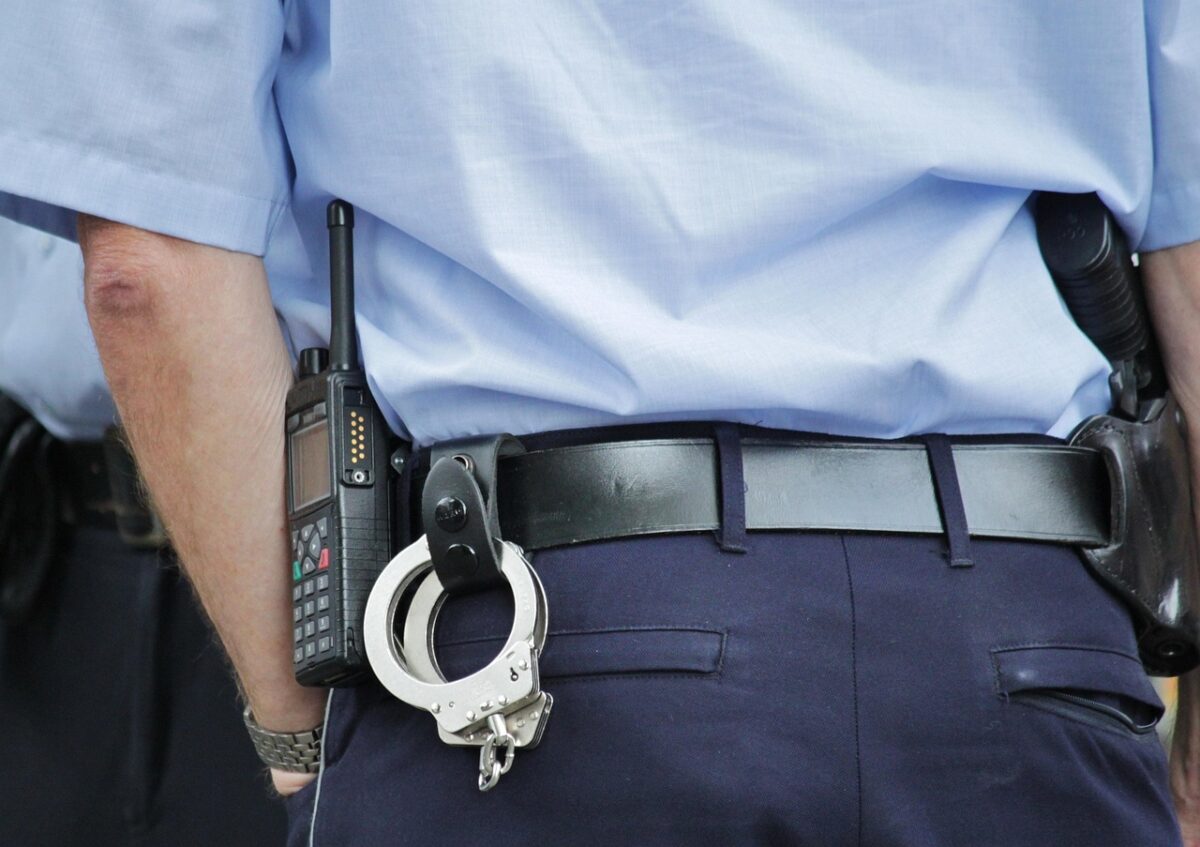 Policajt v uniforme s vysielačkou a putami na opasku, pripravený na službu v uliciach.