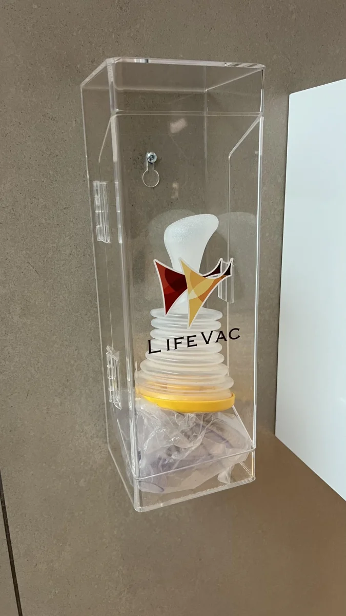 Priehľadná schránka s bezpečnostným prístrojom LifeVac na stene.