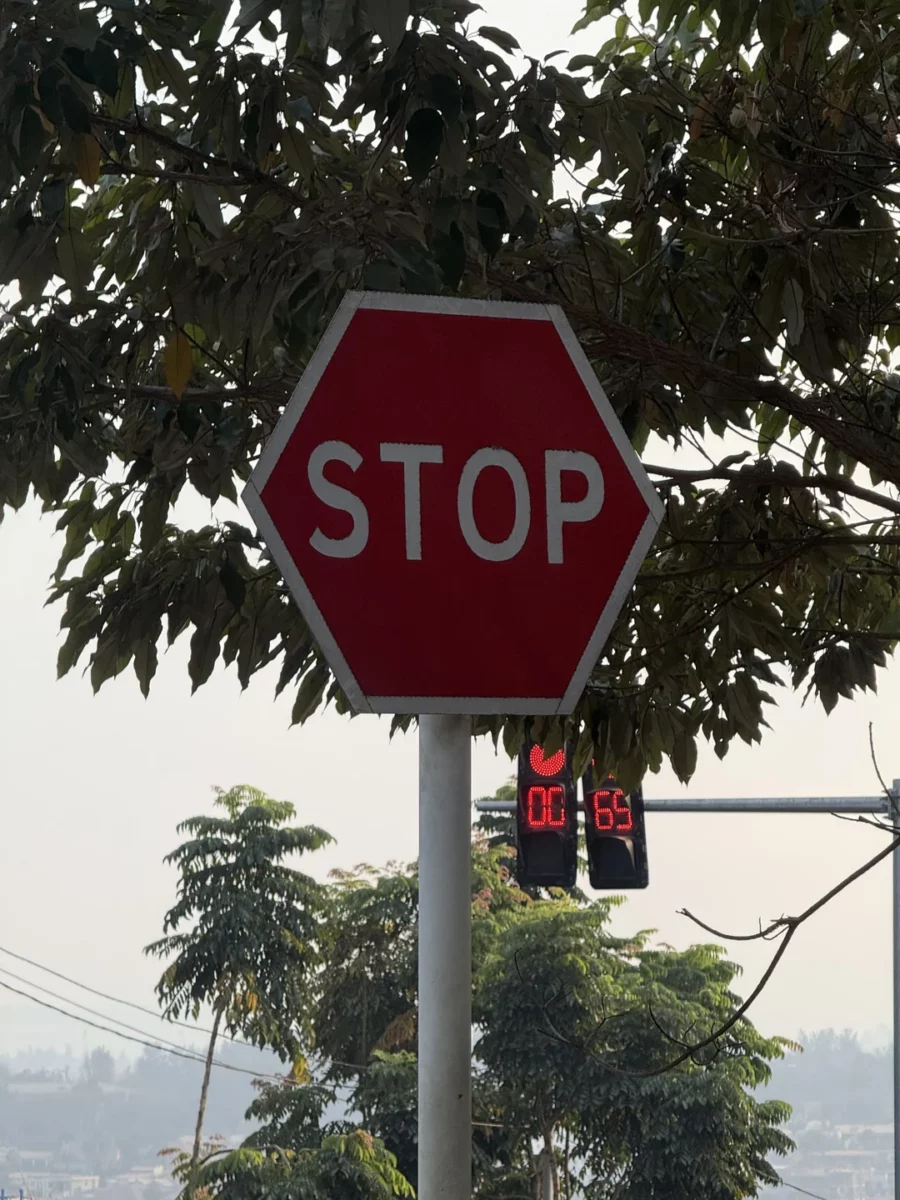Červená stopka pred semaforom, ktorý ukazuje odpočet času, v pozadí stromy a obloha.