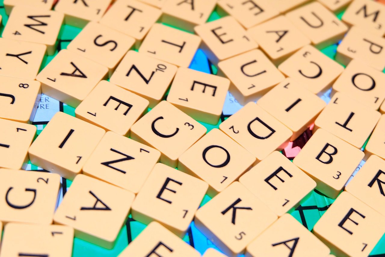 Písmená na hre Scrabble rozptýlené na hracej ploche.