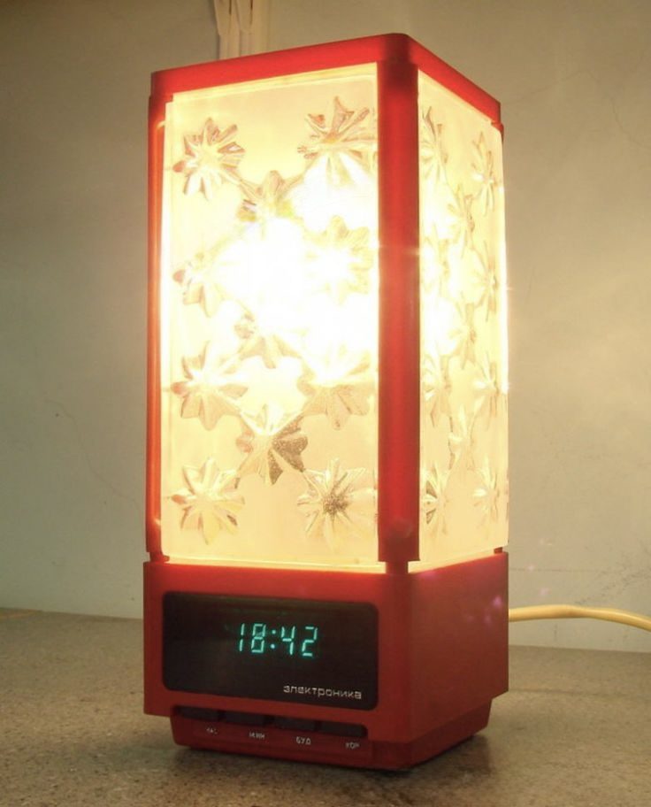 Červená stolná lampa s kvetmi, integrovaný digitálny displej s časom 18:42 na šedom stole.