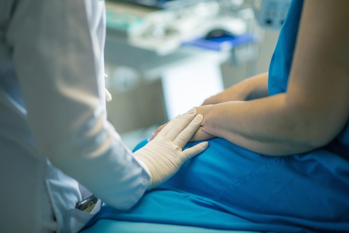 Lekár v rukaviciach poskytuje podporu pacientovi na zdravotníckej kontrole.