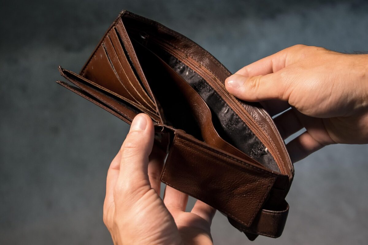 Prázdna hnedá peňaženka držaná v rukách, symbolizuje nedostatok finančných prostriedkov a potrebu rozpočtovania.