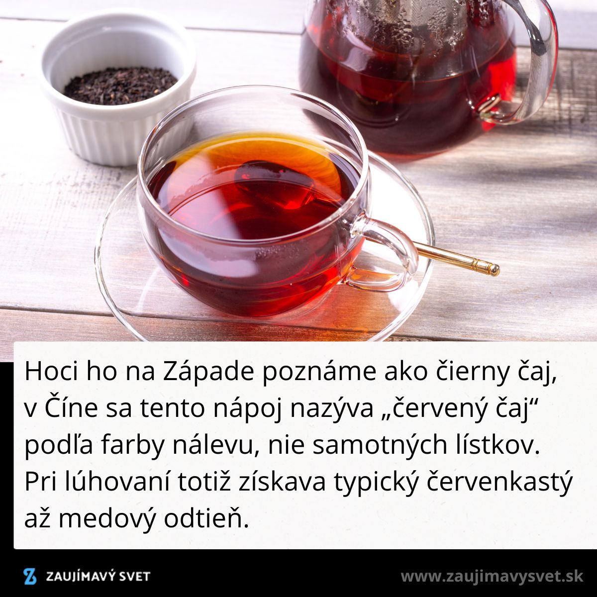 Šálka čierneho čaju so zlatou lyžičkou na drevenom stole, v pozadí kanvica a miska s čajovými lístkami.