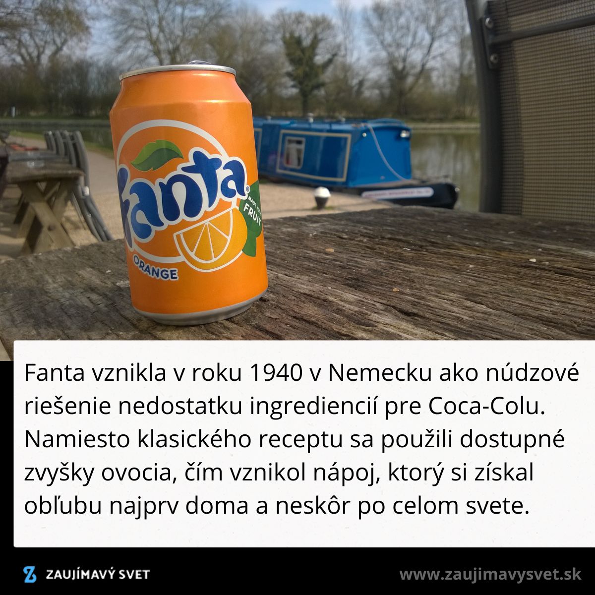 Plechovka pomarančovej Fanty na stole pri vode, modrá loď v pozadí.