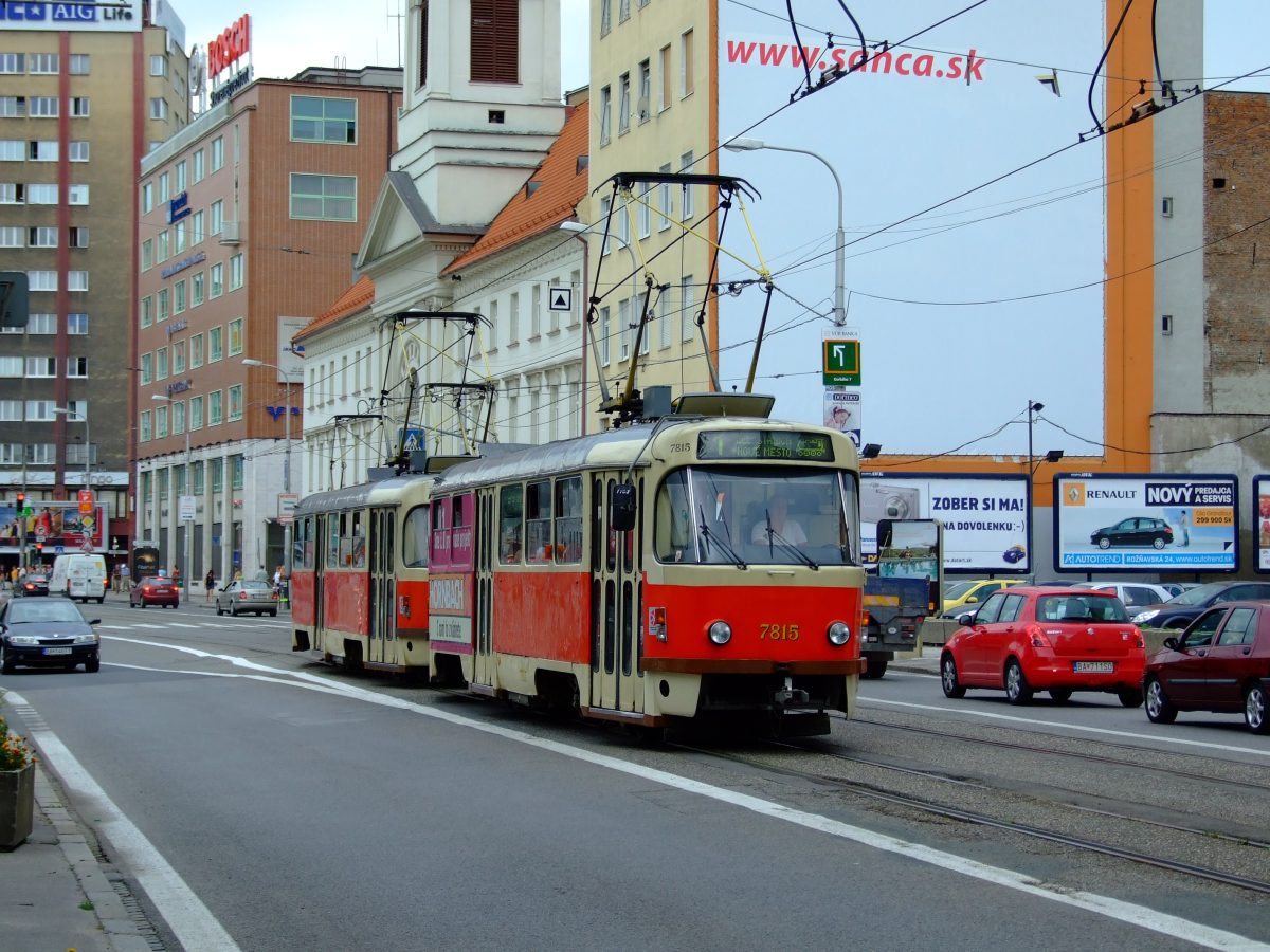Električka v Bratislave prechádza mestom, obklopená historickými budovami a modernými billboardmi.
