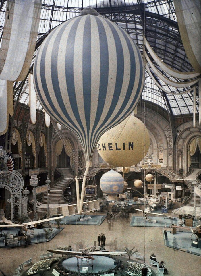 Historická výstava teplovzdušných balónov pod zastrešenou halou s dekoráciami v industriálnom štýle.