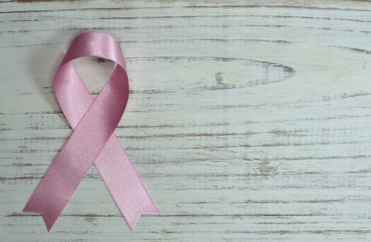 Ružová stužka na drevenom povrchu symbolizuje povedomie o rakovine prsníka.