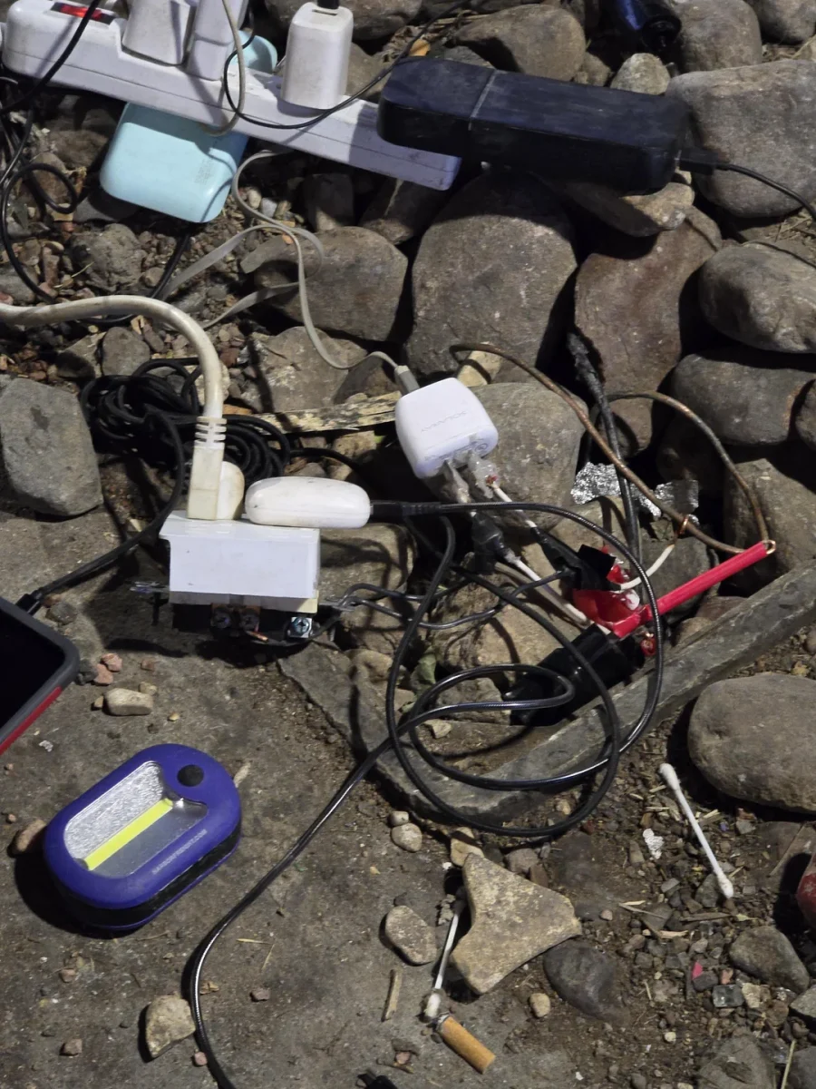Elektrické káble a nabíjačky roztrúsené na kamennom povrchu v neporiadku.