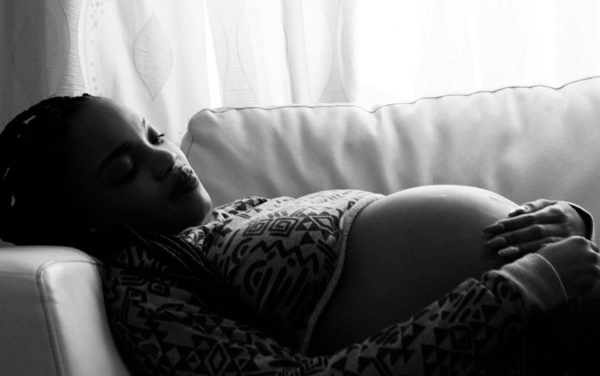 Tehotná žena odpočívajúca na pohovke, čiernobiela fotografia.