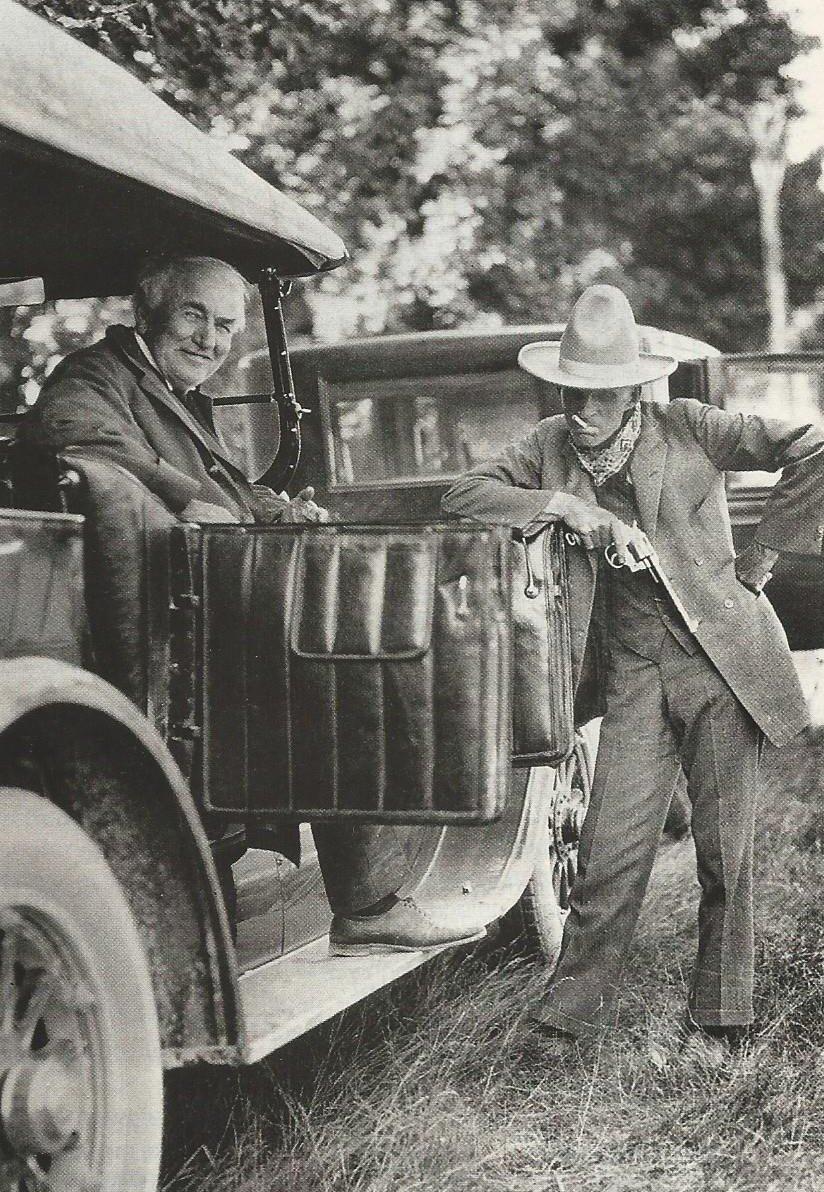 Dva muži pri historickom automobile, jeden sedí v aute, druhý stojí vonku a opiera sa o dvere.