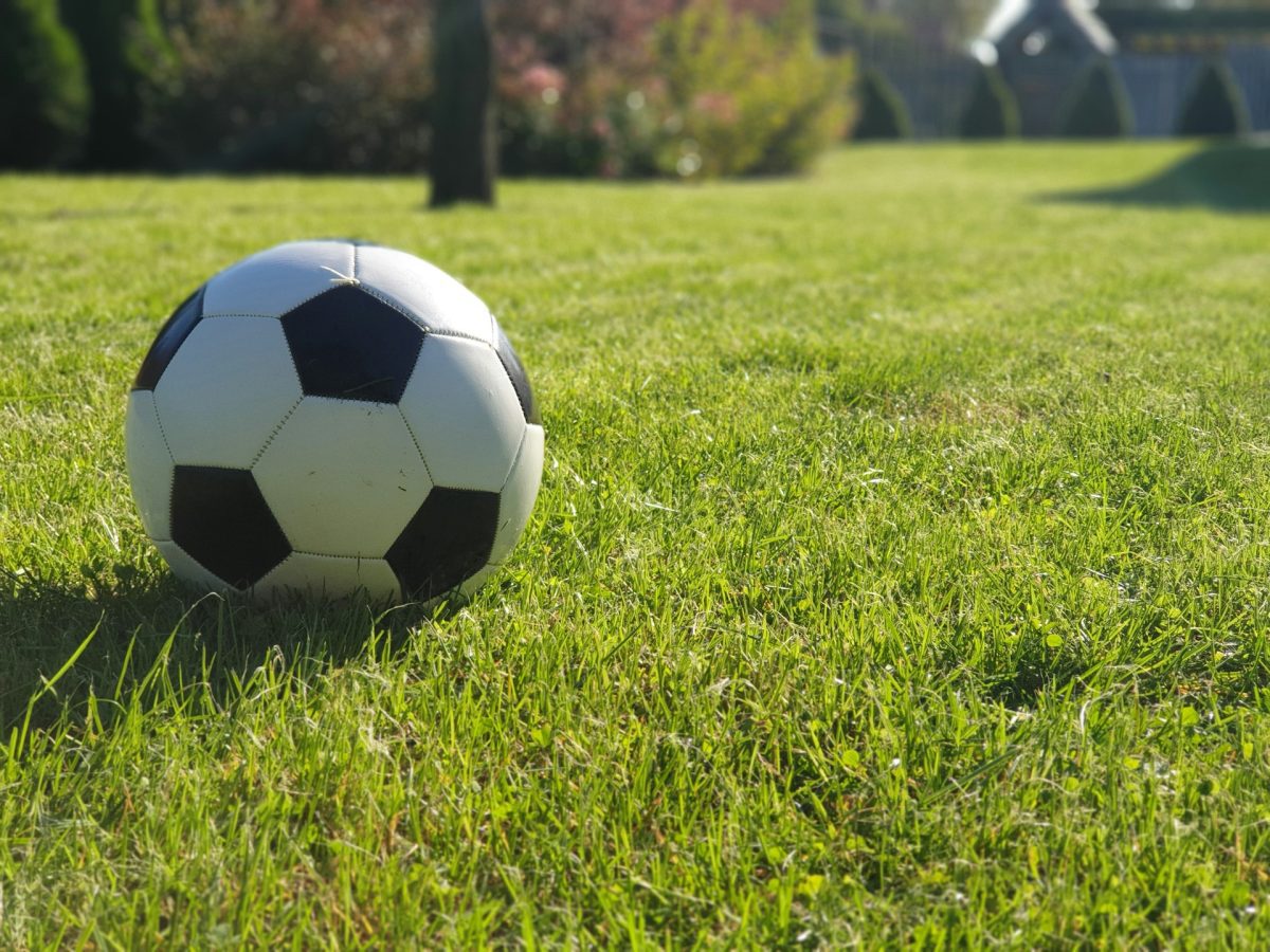 Futbalová lopta leží na zelenej tráve počas slnečného dňa v parku. Ideálne prostredie pre športové aktivity.