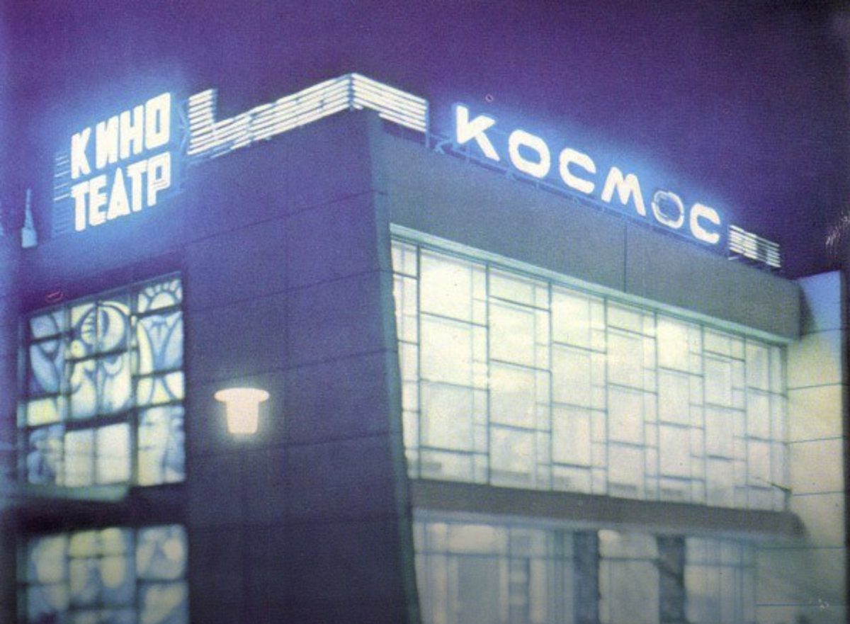 Nočný pohľad na neonové osvetlenie kina s názvom Kosmos na fasáde modernej budovy.