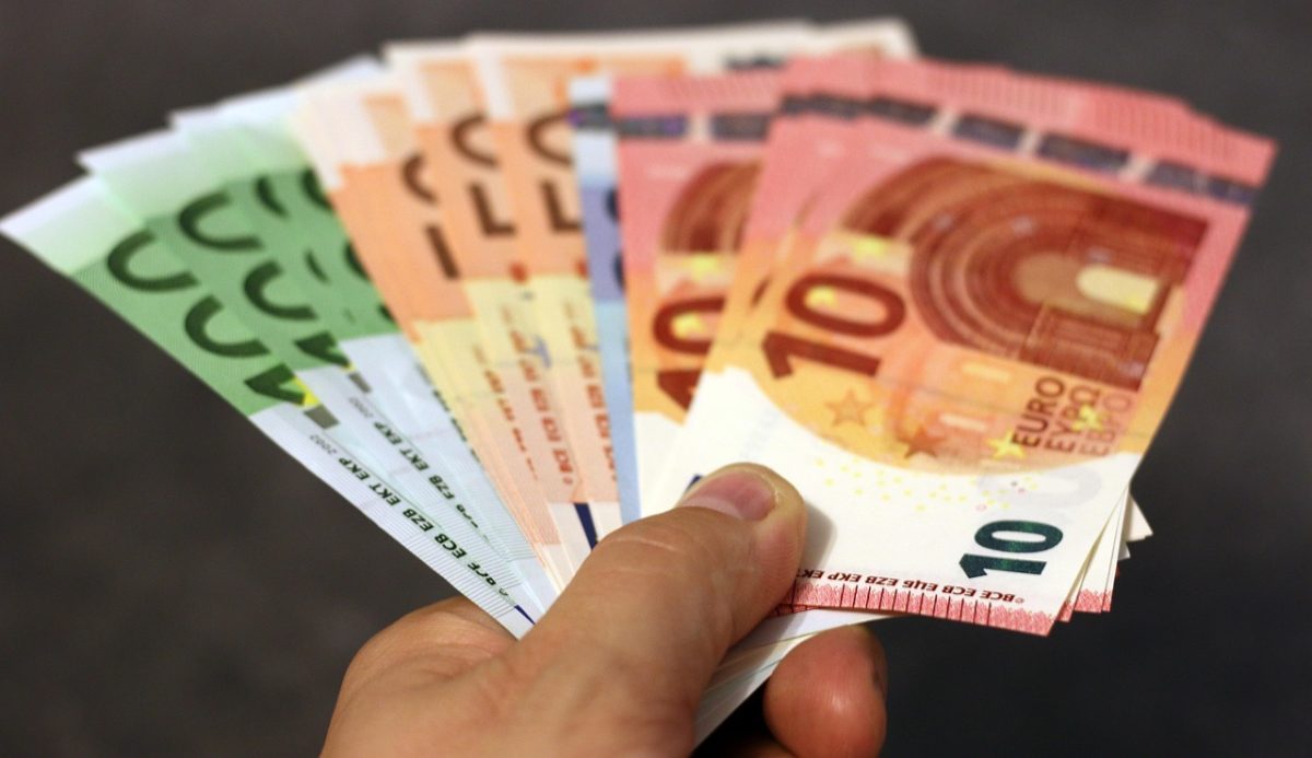 Ruka drží vejárovito rozložené eurobankovky rôznych nominálov, zameranie na detail farebných peňazí.
