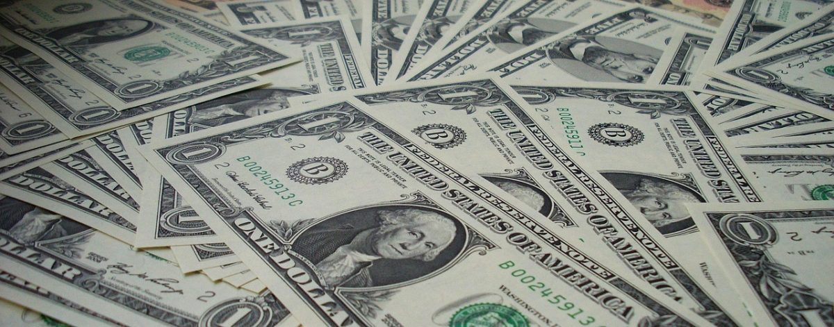 Hromada amerických dolárových bankoviek rozložených na sebe, predstavuje bohatstvo a financie.
