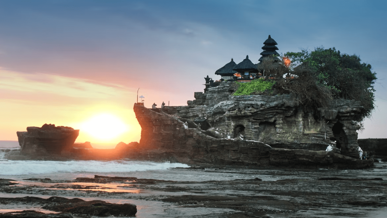 Chrám Tanah Lot na Bali pri západe slnka, obklopený magickou morskou scenériou.