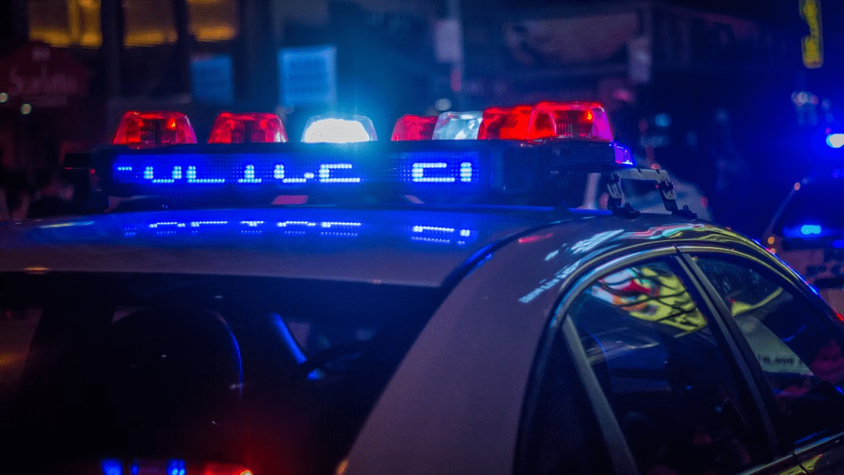Policajné auto so zapnutými majákmi vo večernej mestskej scéně.