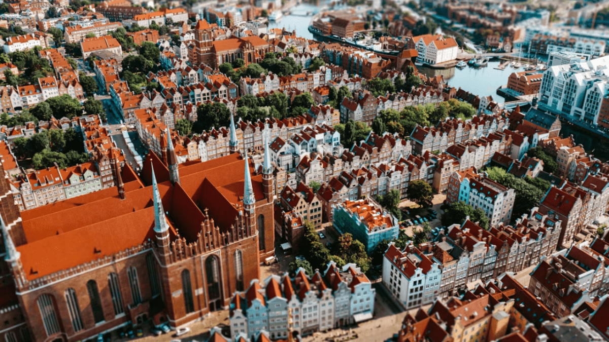 Letecký pohľad na historické mesto s červenými strechami a gotickou architektúrou pri rieke.