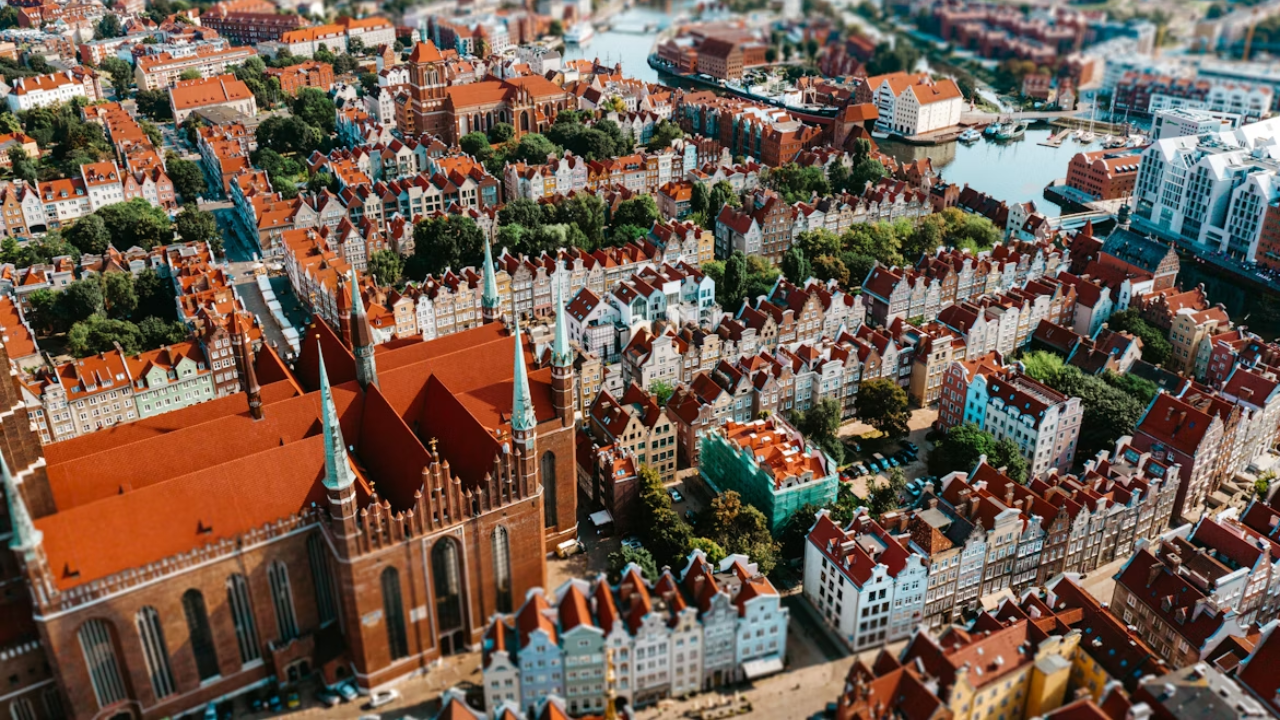 Letecký pohľad na historické mesto s červenými strechami a gotickou architektúrou pri rieke.