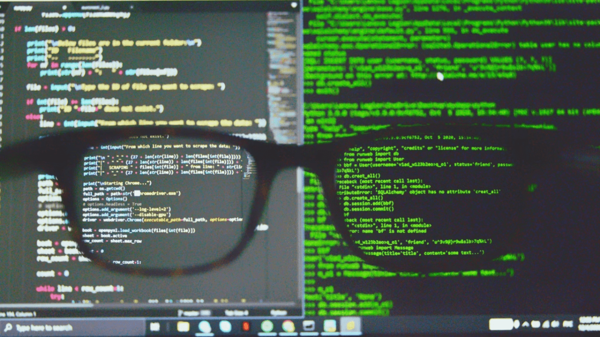 Okuliare pred obrazovkou s kódom na počítači, programovanie a analýza dát.