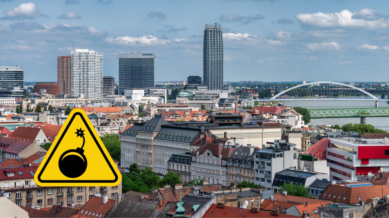 Panoráma mesta s výstražným symbolom bomby na popredí.
