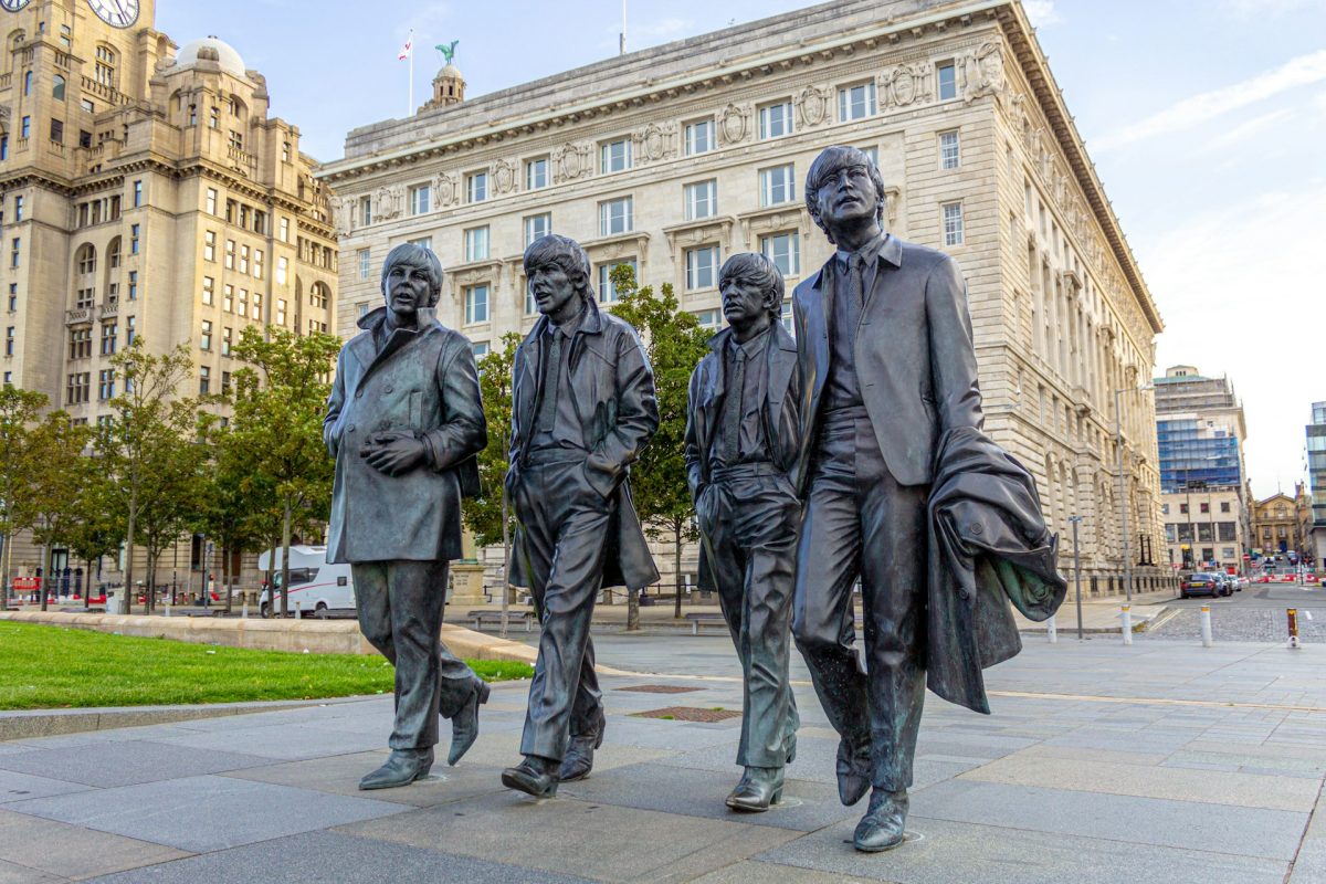 Sochy štyroch mužov v saku pred historickými budovami, Liverpool, Anglicko.