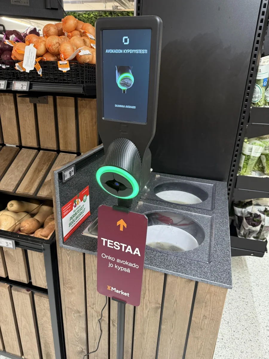 Zariadenie na testovanie zrelosti avokáda v obchode, vedľa regálu so zeleninou.