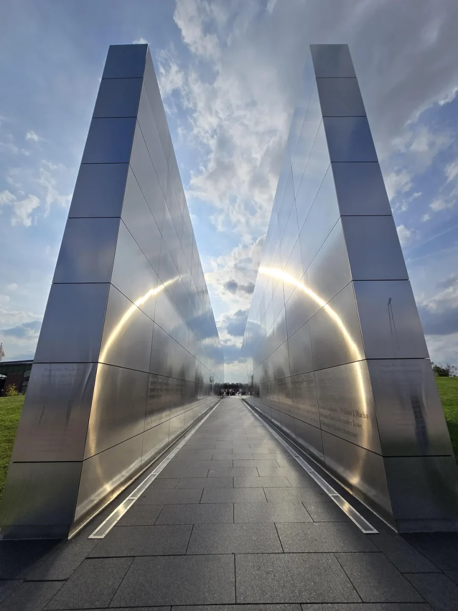 Moderná oceľová monumentálna architektúra smerujúca k oblohe, odrážajúca slnečné lúče v mestskom prostredí.
