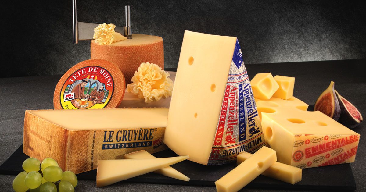 Rôzne druhy švajčiarskych syrov - Tête de Moine, Le Gruyère, Appenzeller a Emmental s hroznom a figami.