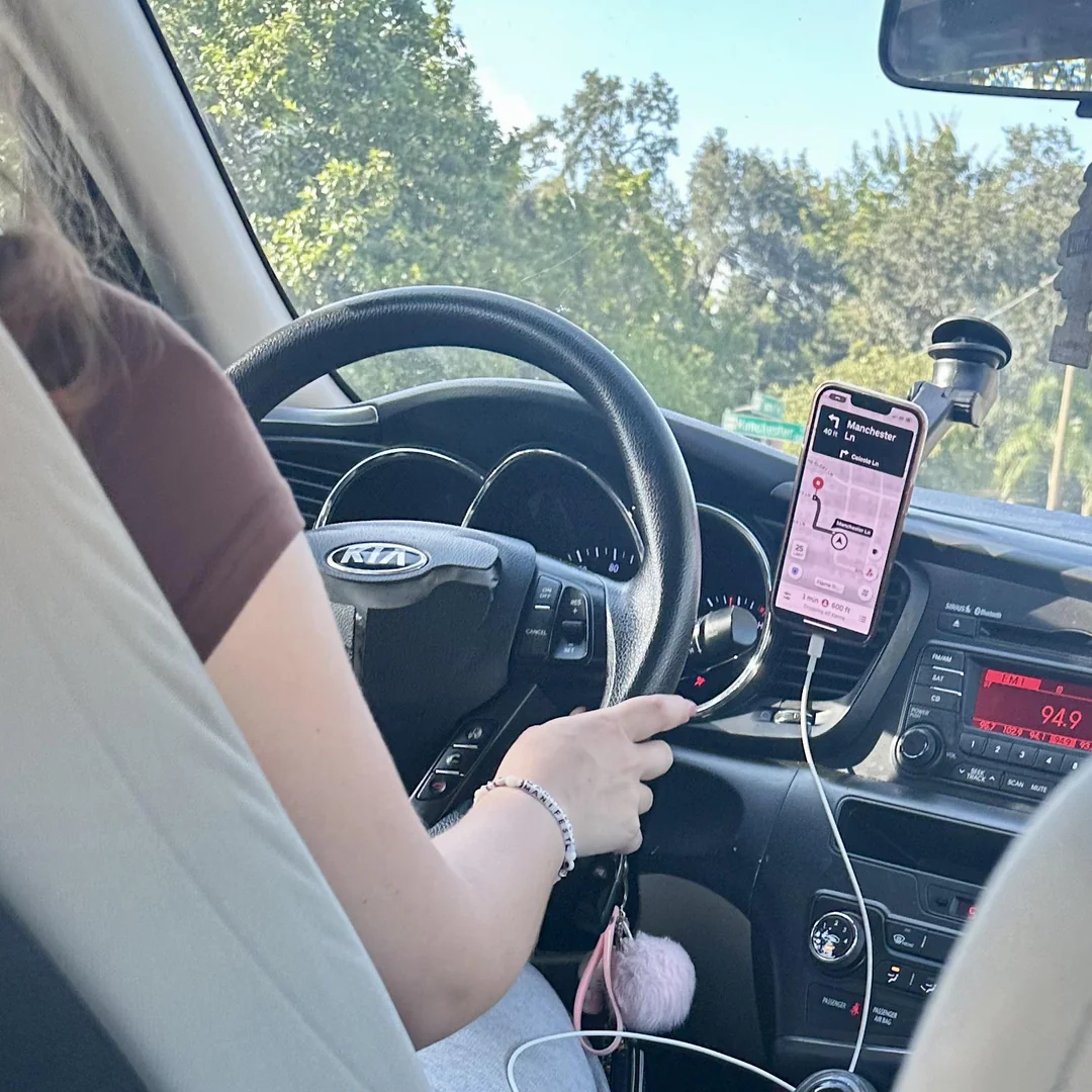 Vodička drží volant auta, GPS navigácia ukazuje trasu do Manchesteru.
