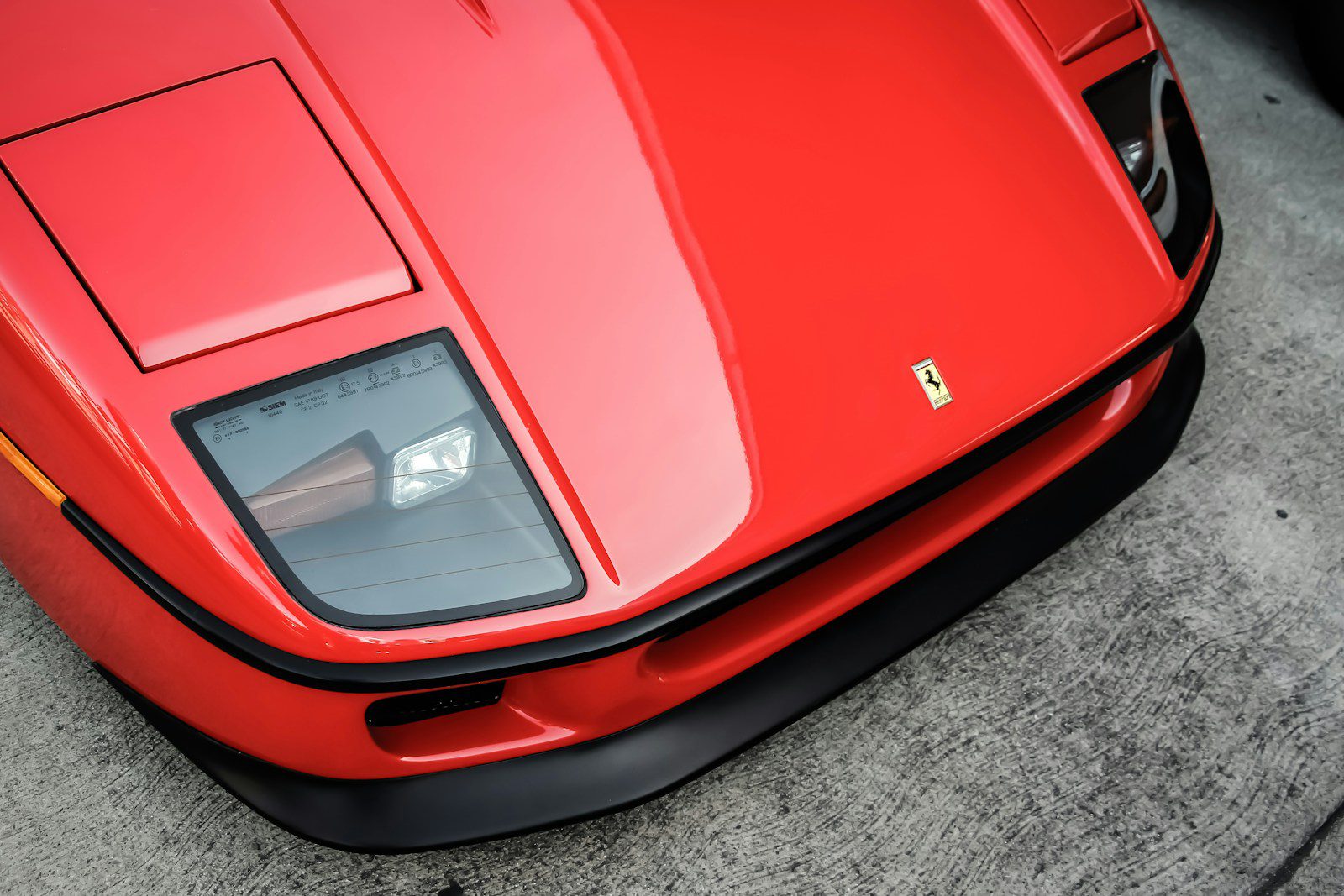 Červené športové auto ferrari s detailným pohľadom na prednú kapotu a svetlomet.