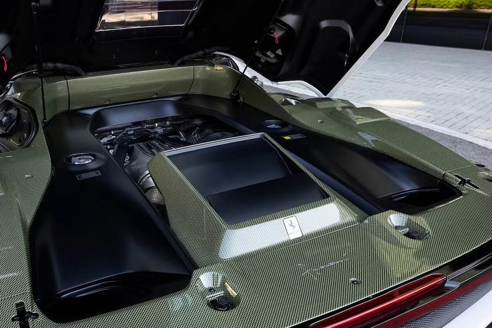 Motor Ferrari pod kapotou športového auta, detailný pohľad na technické komponenty a dizajn.