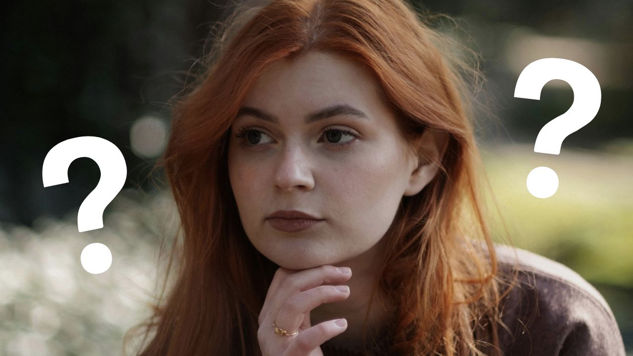 Žena s rušavými vlasmi premýšľa, obklopená otáznikmi, hľadá odpovede v parku na zamyslenie.