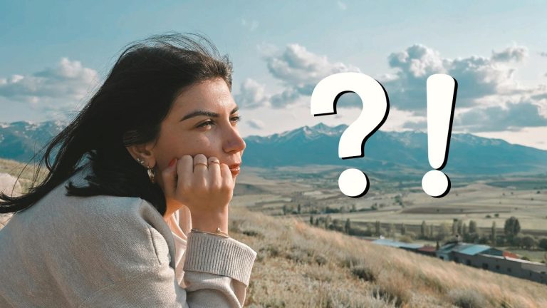 Žena v prírode premýšľa, hory v pozadí a otáznik s výkričníkom zvýrazňujú jej zamyslenie.