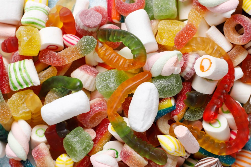 Rôznofarebné želé cukríky a marshmallow v tvare hadíkov a valčekov, sladkosti na bielom pozadí.