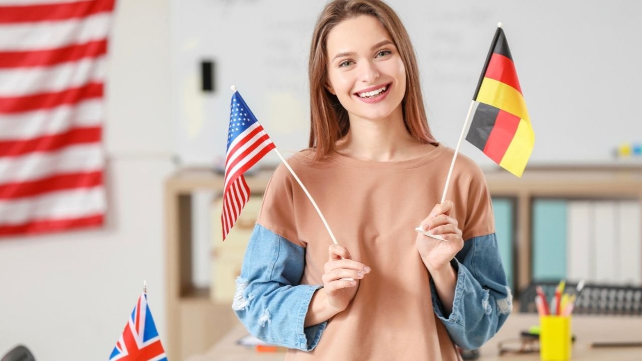 Osoba v triede drží vlajky USA a Nemecka, symbolizujúce výučbu jazykov.