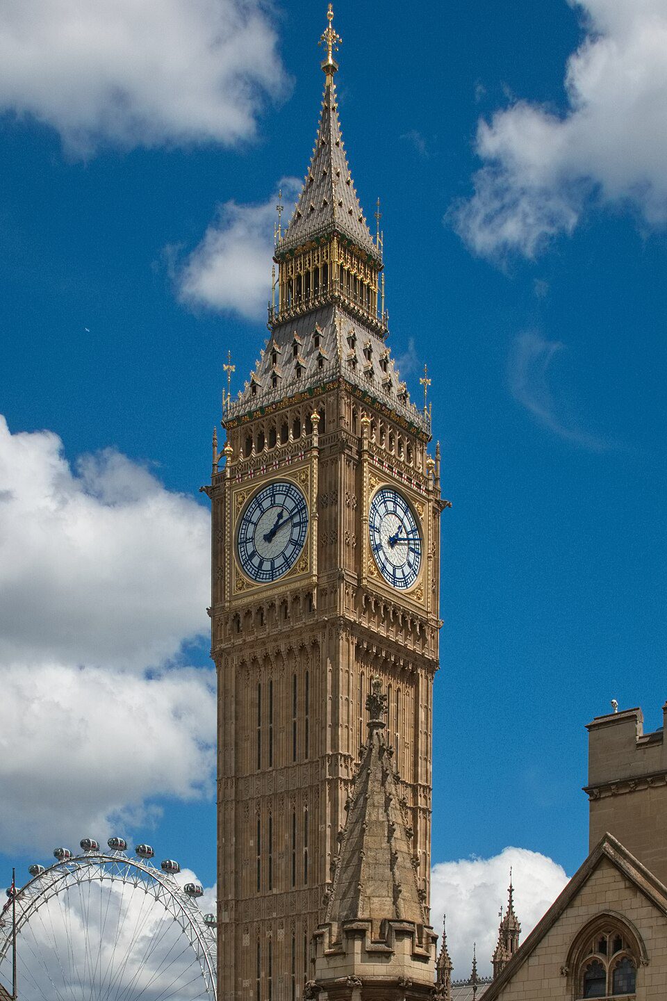 Hodiny Big Ben na pozadí modrej oblohy, vedľa Londýnskeho oka a historických budov.