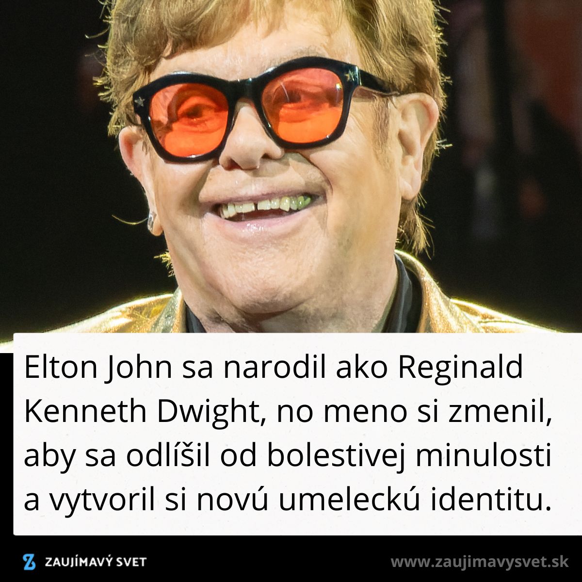 Osoba na pódiu s červenými okuliarmi a úsmevom počas vystúpenia.