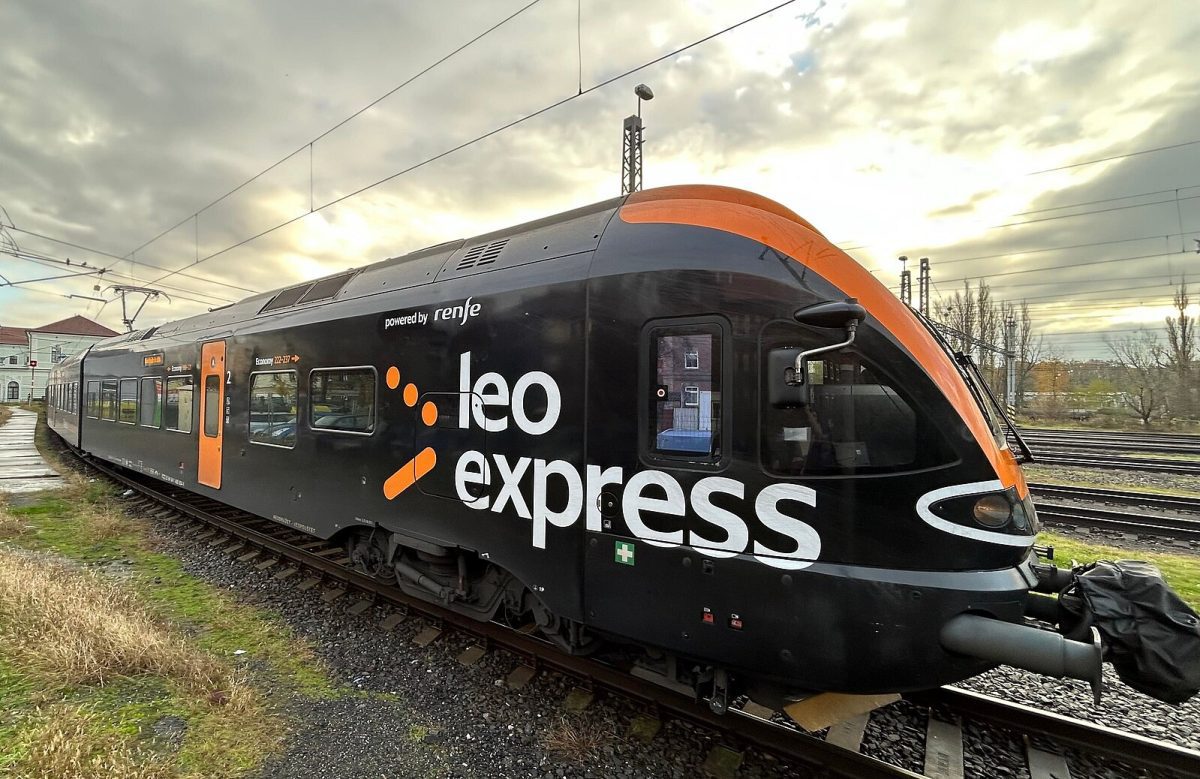 Vlak Leo Express stojí na trati pri západe slnka, pripravený na ďalšiu cestu.