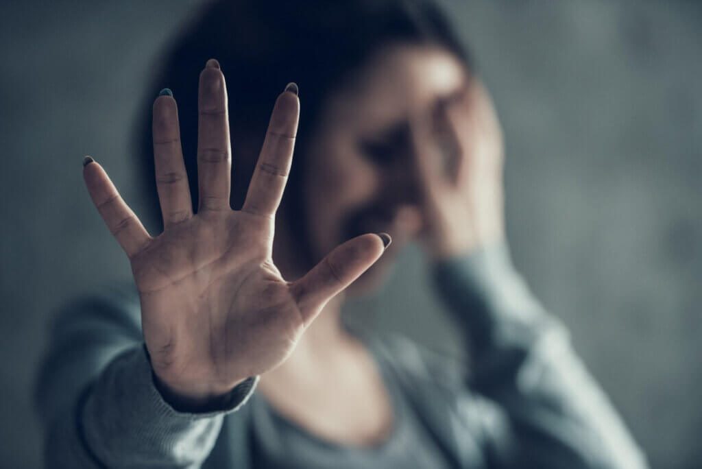 Žena s rozmazanou tvárou dáva stop gesto, zdvihnutá ruka v popredí.