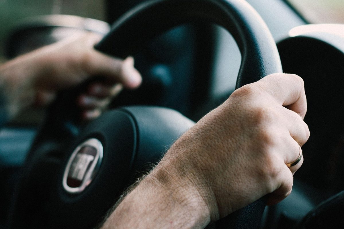 Ruky vodiča držiace volant automobilu značky Fiat, detailný pohľad na riadenie vozidla počas jazdy.